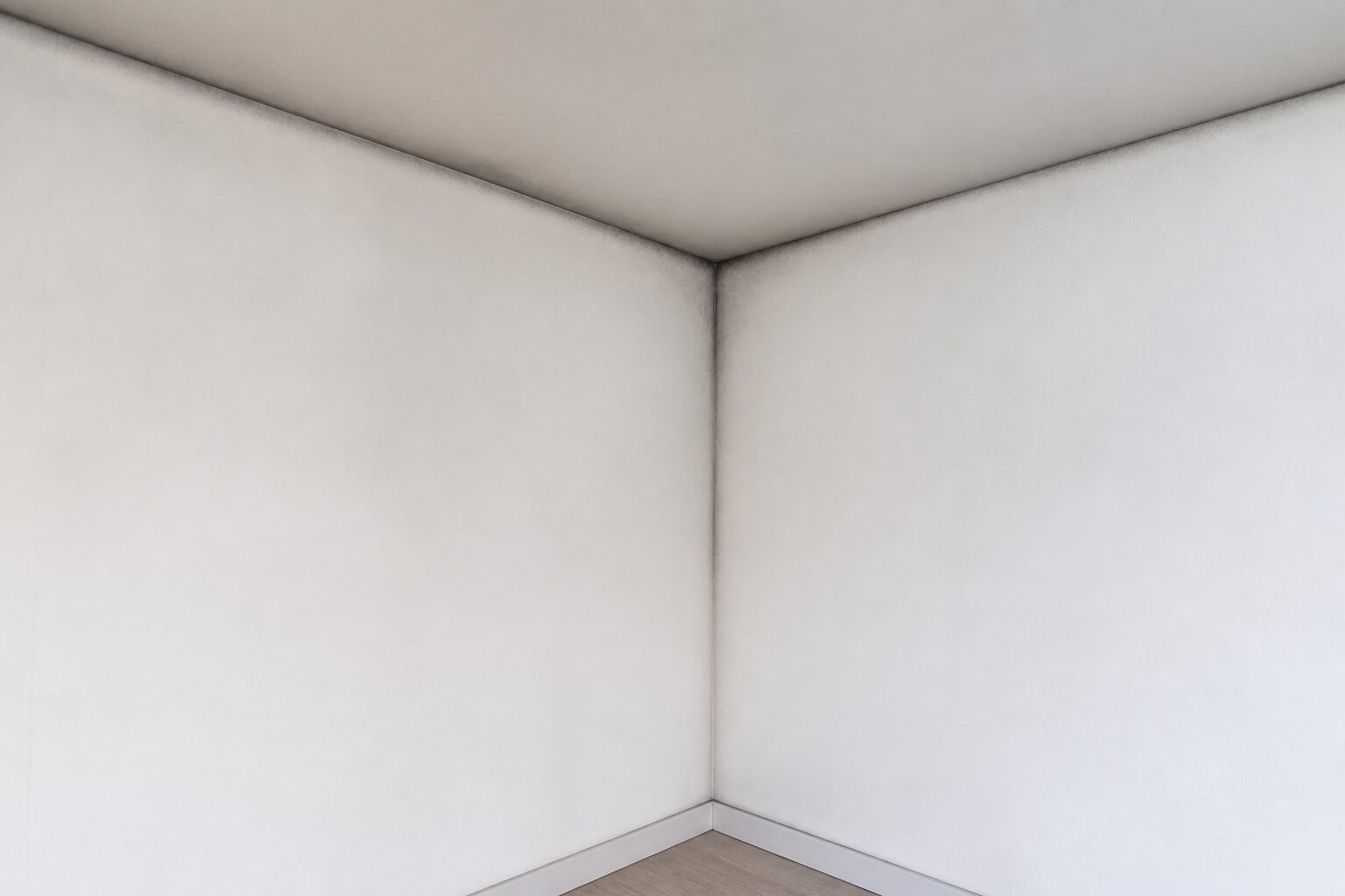 Raumecke an der Außenwand mit schmalem dunklem Streifen entlang der Kanten als Zeichen einer Wärmebrücke